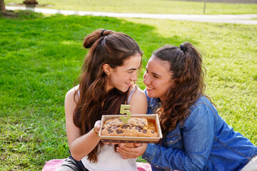 Romantic young couple celebrating with a cookie cake in a park