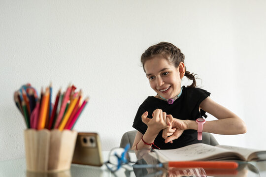 Young disabled girl with tracheostomy watching drawing tutorial on phone
