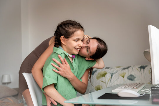 Disabled girl with tracheostomy being embraced by sister at home
