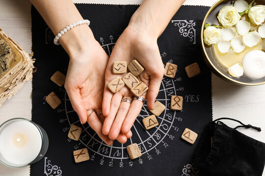 Woman with wooden runes at table, top view
