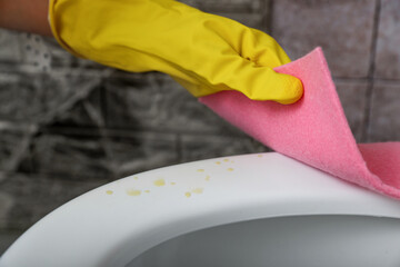 Woman wiping urine drops from toilet seat in restroom, closeup