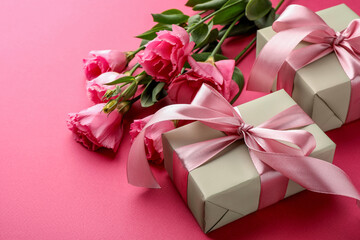 Beautiful gift boxes with bows and eustoma flowers on pink background