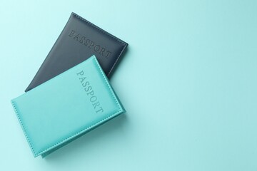 Passports in color covers on light blue background, top view. Space for text