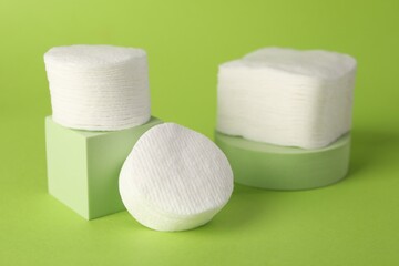 Clean cotton pads on green background, closeup