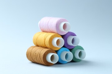 Spools of colorful sewing threads on light background, closeup