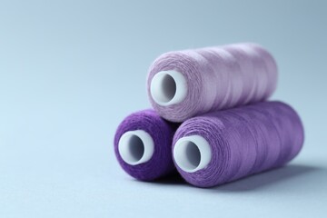Spools of colorful sewing threads on light background, closeup. Space for text