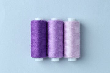 Spools of colorful sewing threads on light background, flat lay