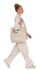 Fashionable woman in a beige suit and carrying a tote bag walking in profile side towards the...