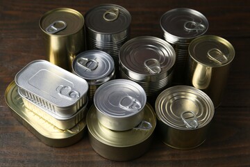 Many closed tin cans on wooden table, closeup
