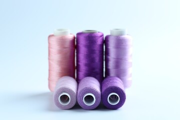 Spools of colorful sewing threads on light background, closeup
