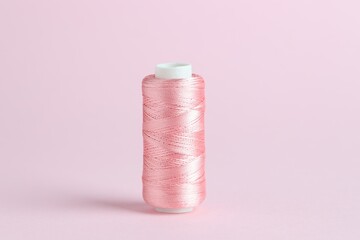 Spool of sewing thread on pink background