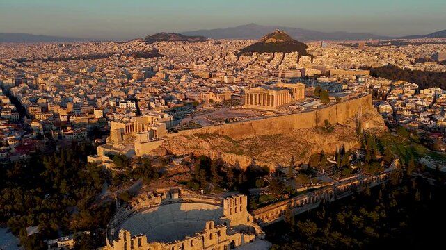 Panoramic aerial view of the Parthenon Temple and the Odeon of Herode theatre at the Acropolis of Athens, Greece, in golden sunset light