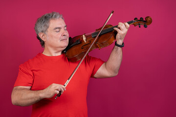 Musician playing viola with closed eyes on pink background
