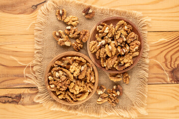 Shelled walnuts with kitchen utensils on a wooden table, close-up, top view.