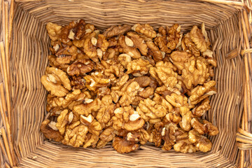 Shelled walnuts in a basket, close-up, top view.