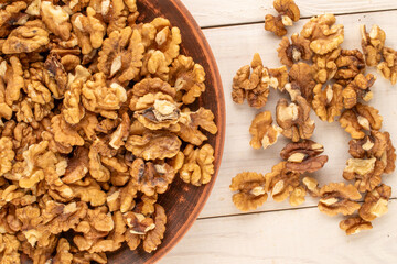 Shelled walnuts with kitchen utensils on a wooden table, close-up, top view.