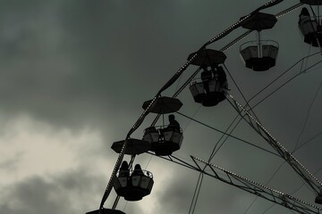 Silhouetted Ferris Wheel on Moody Cloudy Evening Sky