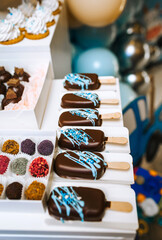 Candy bar, lots of decorated sweets on the table: chocolate ice cream, marshmallows, cupcakes, cookies, cake, cream pastries, cake. Food photography.