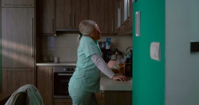 Exhausted nurse stressed in kitchen after a hard day at work in a hospital, standing and thinking feeling depressed and mental tension