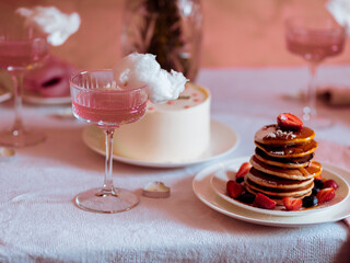 Festive table setting with pancakes, cocktails, cotton candy in pink tones