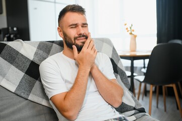 Young man suffering from toothache at home