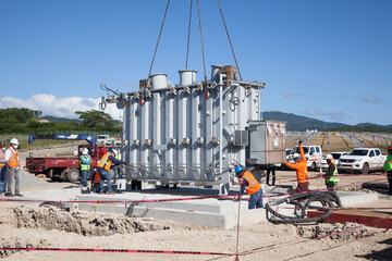 Men's installing a transformer in a solar farm substation 