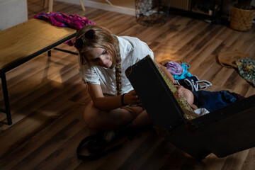 A Young Girl Engaged in the Delightful Exploration of a Vintage Chest Within a Cozy Room