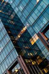 A modern glass office building with reflective windows at an angle. Captures urban architecture, reflections, and contemporary design, showcasing geometric patterns and vibrant city life