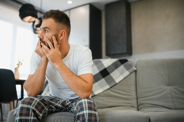 Obraz premium Young man suffering from strong headache or migraine, morning after hangover concept