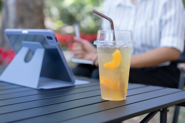 Close-up photo of a plastic drinking glass Fruit juice drink with peach pulp in a drinking glass. Cold drinks To refresh on the background of a young businesswoman sitting in a meeting or working.