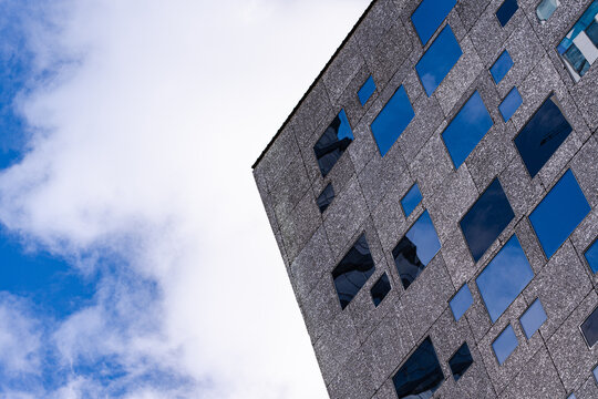 Fototapeta Modern building facade with blue windows against cloudy sky