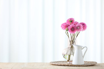Beautiful pink flowers in vase on wooden table at home. Space for text