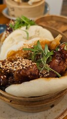 Savory Asian-inspired dish served in a bamboo steamer.  Tender meat, sesame seeds, and fresh herbs atop fluffy buns.