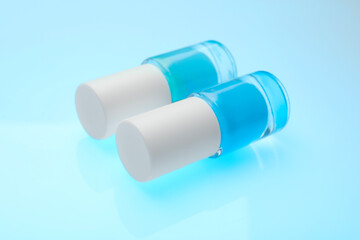 Nail polish in bottles on light blue background, closeup