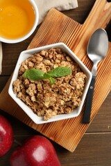 Tasty apple crisp in bowl, fresh fruits, honey and spoon on wooden table, flat lay