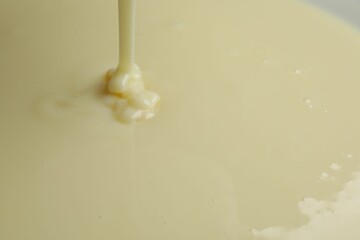 Pouring delicious condensed milk as background, closeup