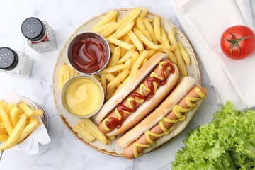 Tasty hot dogs with fries served on white marble table, flat lay