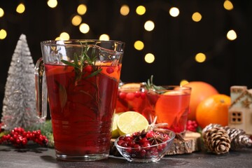 Tasty punch drink and ingredients on dark table against blurred lights