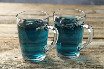 Delicious butterfly pea flower tea in cups on wooden table