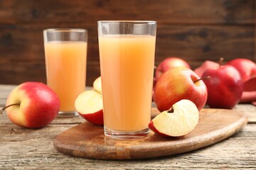 Tasty apple juice in glasses and fresh fruits on wooden table, closeup