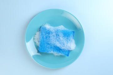 One sponge with foam and plate on light blue background, top view
