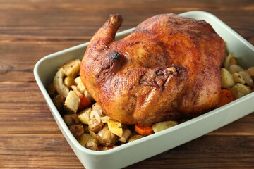 Delicious baked turkey and vegetables in baking dish on wooden table, closeup
