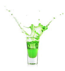 Delicious absinthe splashing in shot glass on white background