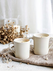 Two handmade ceramic mugs with delicate heart designs, placed on a rustic linen cloth, complemented by dried flowers in soft natural light. Generative AI