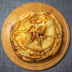 Top view of a platter on a round bamboo cutting board with ready-to-eat pancakes beautifully arranged in a cone.