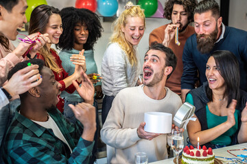 Group of friends celebrating a birthday with cake and gifts. Multicultural gathering with joyful expressions and vibrant decorations. A festive and cheerful atmosphere perfect for a special occasion.
