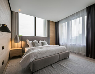 Interior of modern bedroom with white bed and alarm clock on bedside