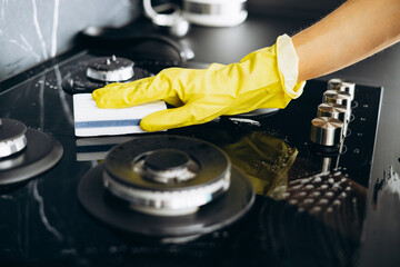 Woman housekeeper cleaning stove surface