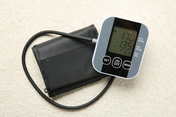 Blood pressure measuring device on light textured background, top view