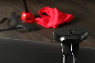 Sex work. Laptop with web camera on wooden surface, closeup